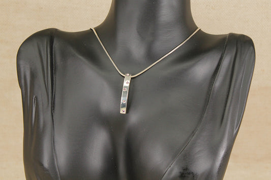 Mannequin wearing a silver pink topaz  pendant necklace on a beige background