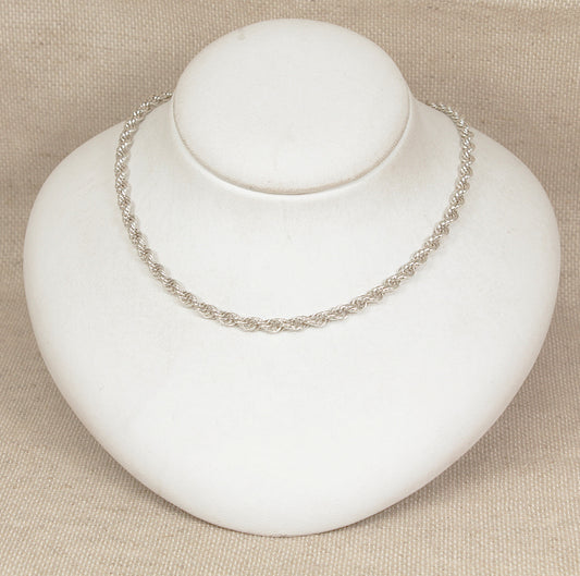 Silver necklace on a white mannequin bust against a beige background