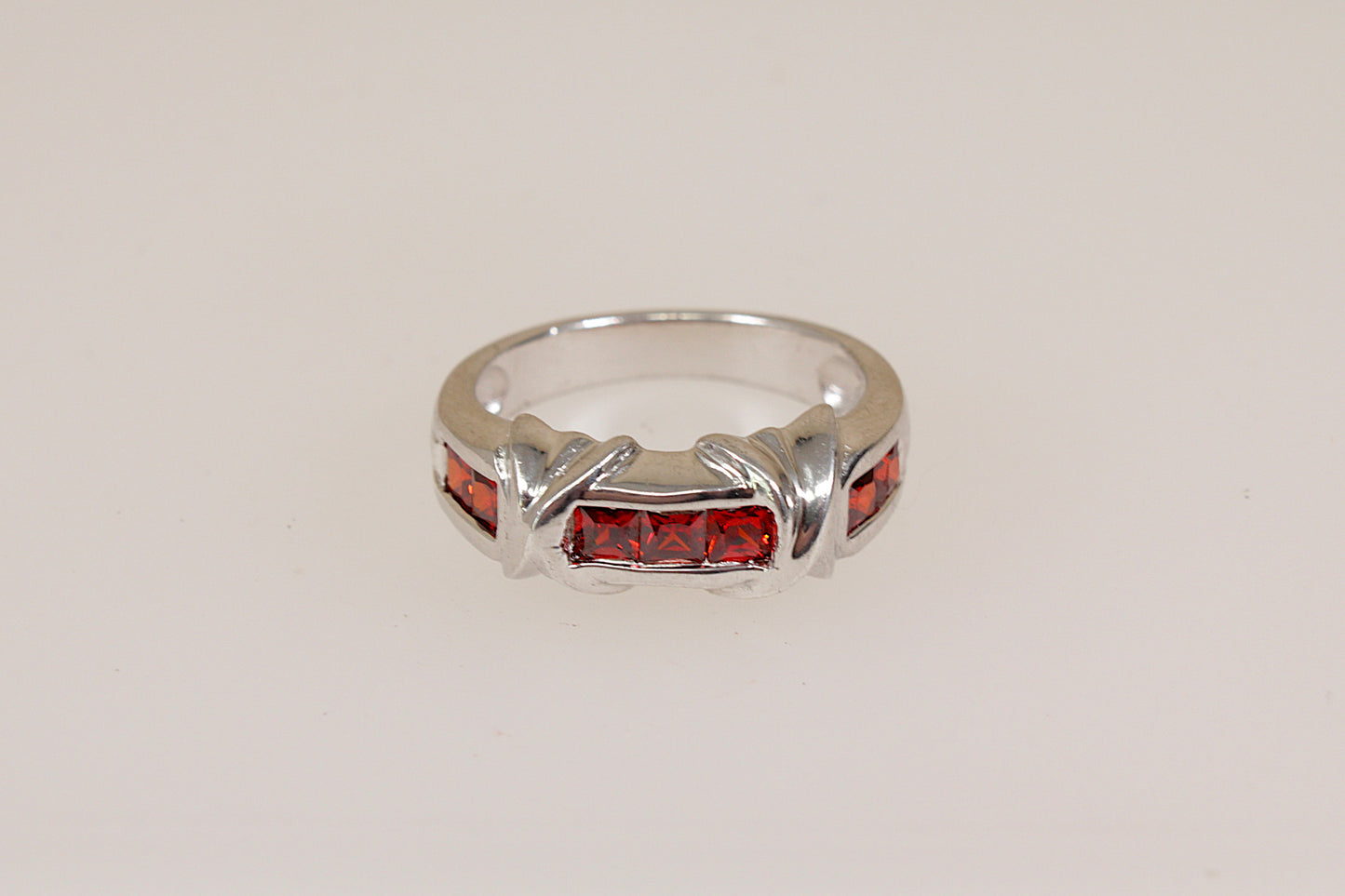 Silver ring with red gemstones on a light gray background