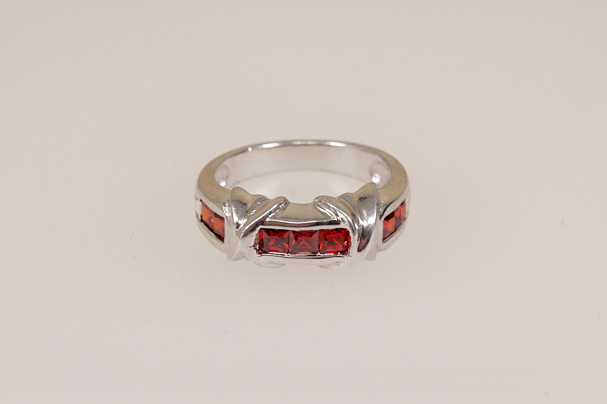 Silver ring with red gemstones on a light gray background