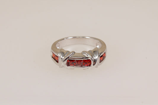 Silver ring with red gemstones on a light gray background