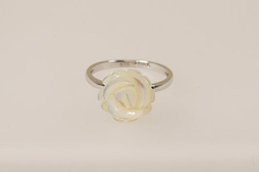 A silver ring with a carved white mother of pearl rose in full bloom on a white background.