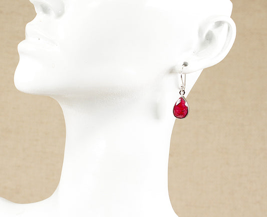 Red teardrop earrings on a white mannequin head with beige background