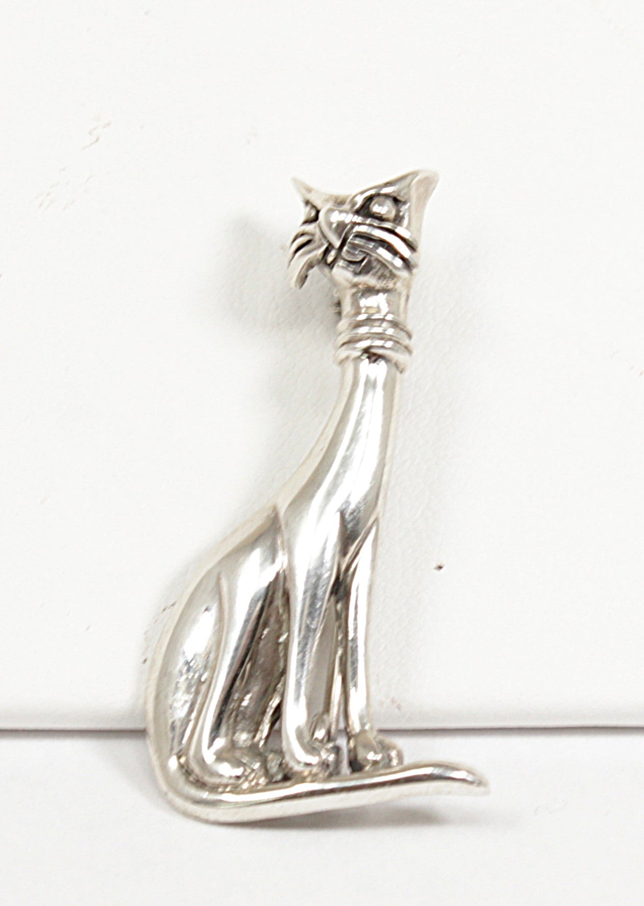 Silver cat-shaped brooch on a white background