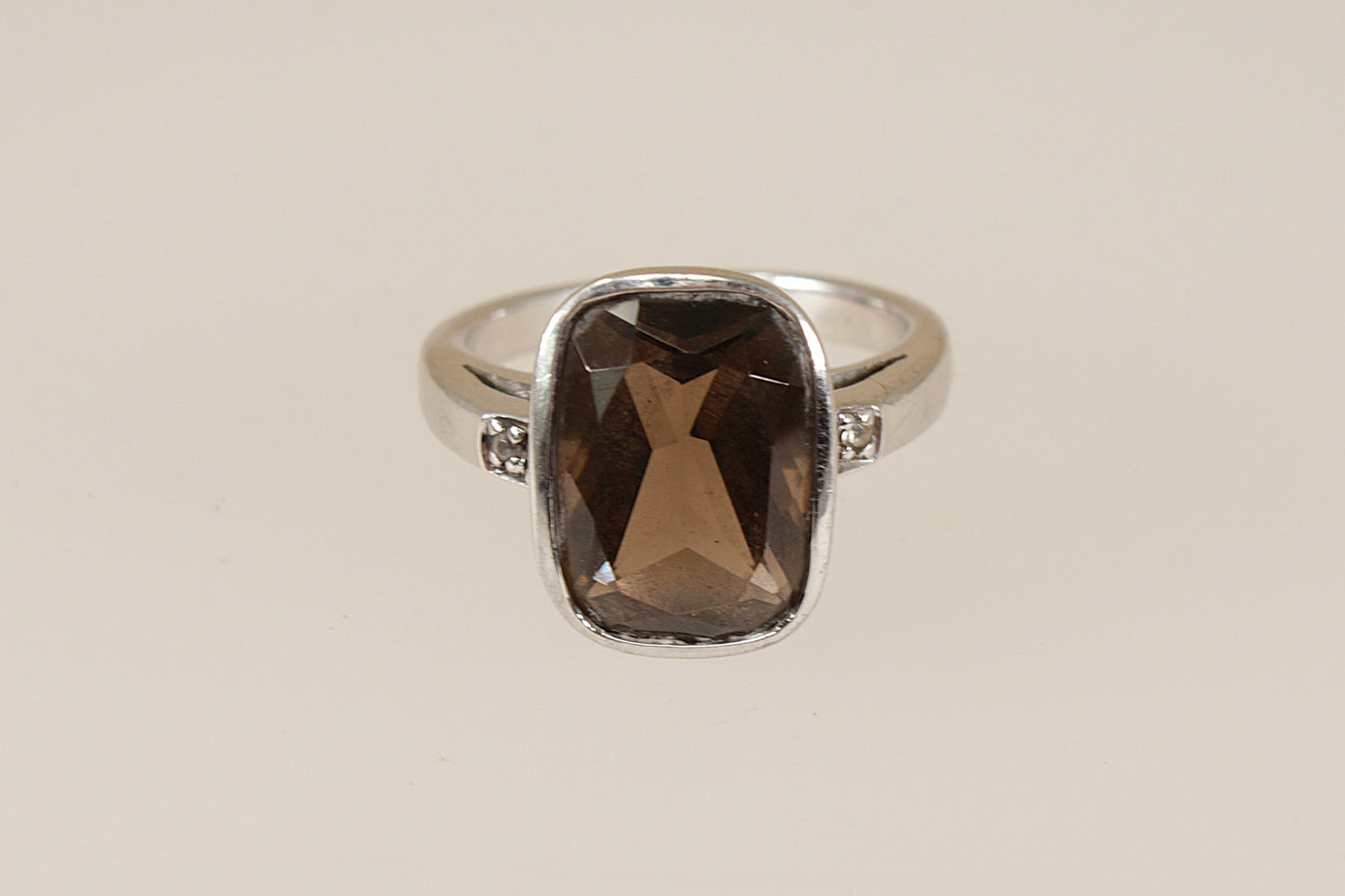 Silver ring with a smoky quartz gemstone on a beige background