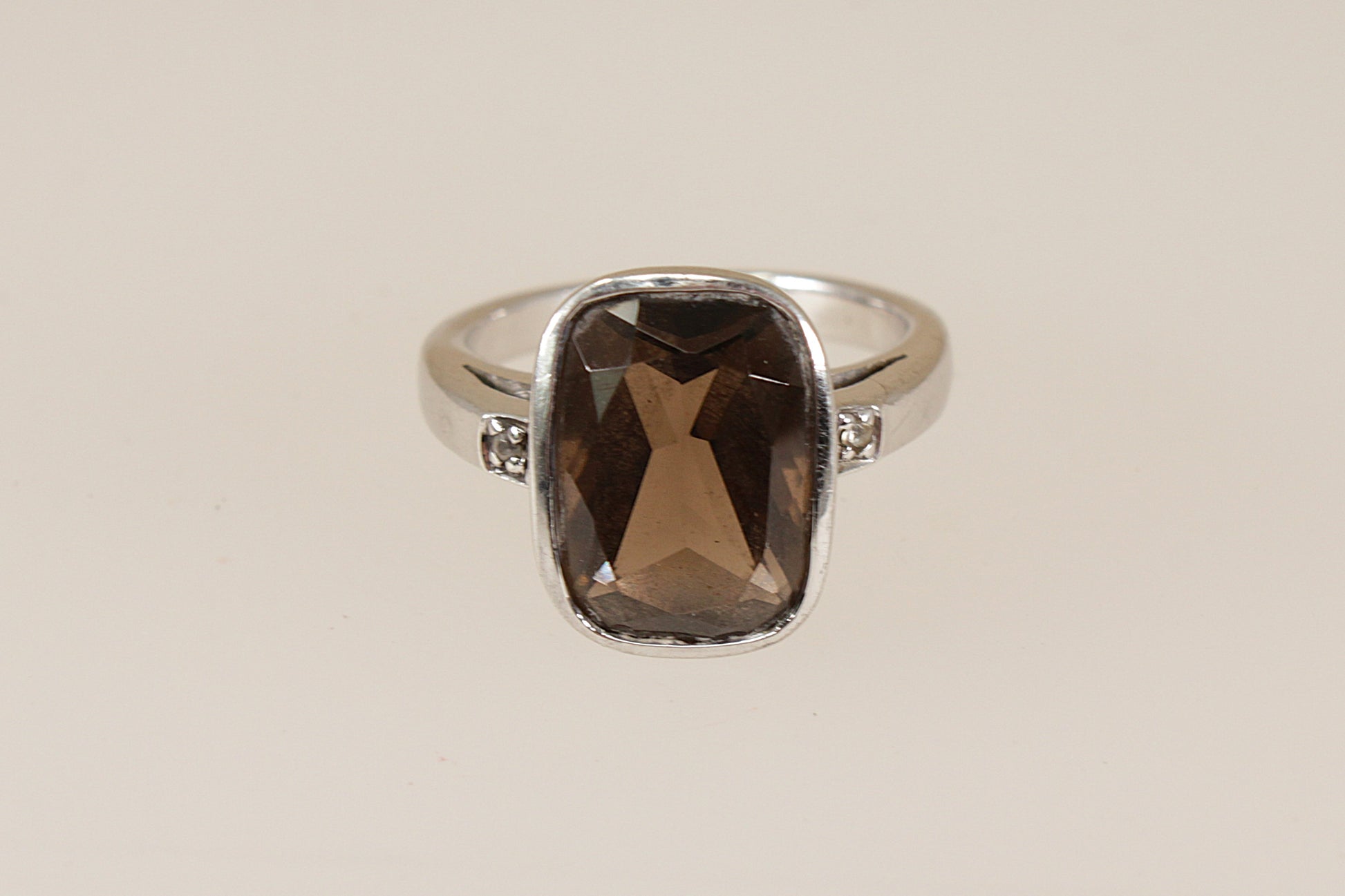 Silver ring with a smoky quartz gemstone on a beige background