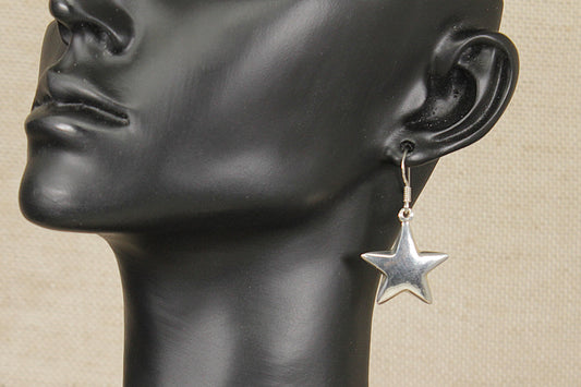 Star-shaped earring on a black mannequin head against a beige background
