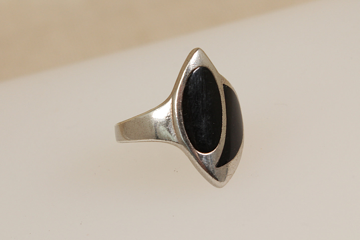 Silver ring with a black inlay on a beige background