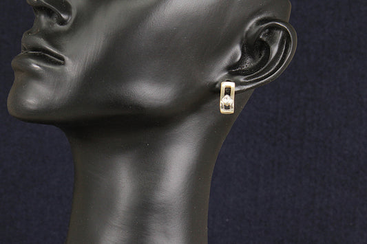 Silver and crystal earring on a black mannequin ear against a dark background