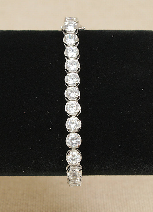 Silver bracelet with clear gemstones on a black stand
