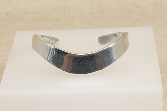 Silver bracelet on a white card with a beige background