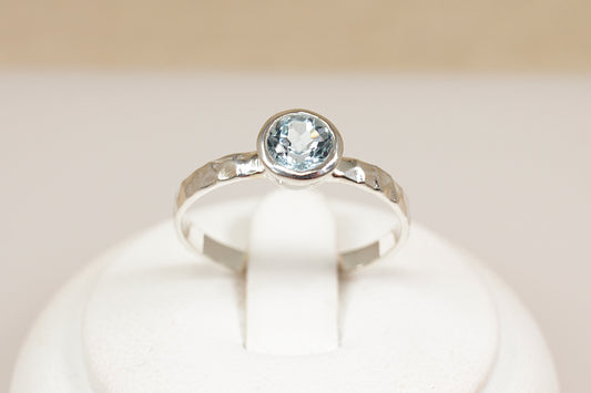 Silver ring with a blue gemstone on a white background