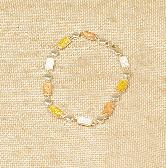 A silver bracelet with three shades of silver, displayed on a textured background.