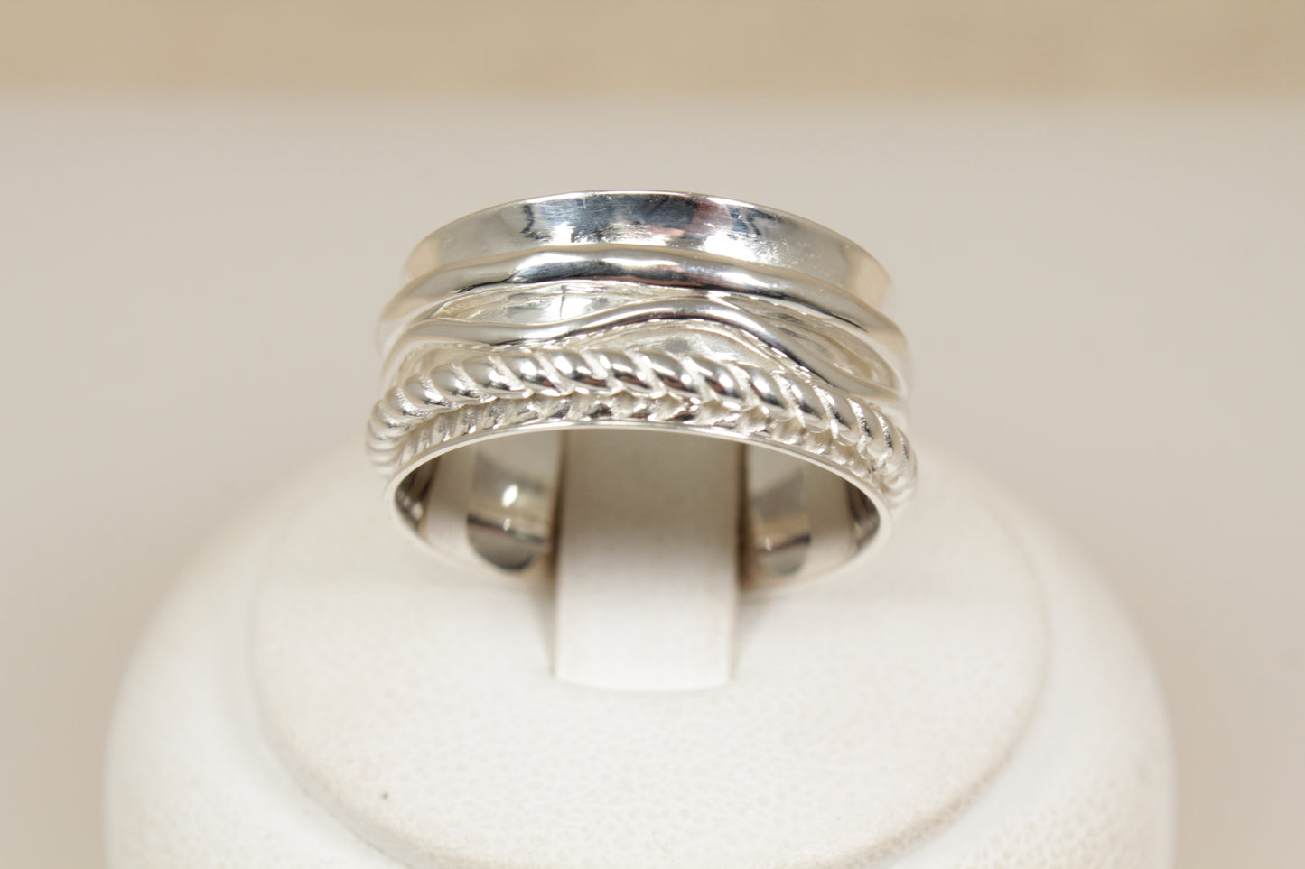 Silver ring with intricate design of three spinning bands on a white background