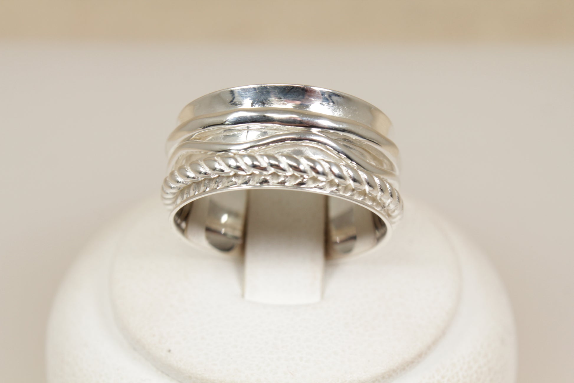 Silver ring with intricate design of three spinning bands on a white background