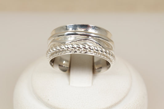 Silver ring with intricate design of three spinning bands on a white background