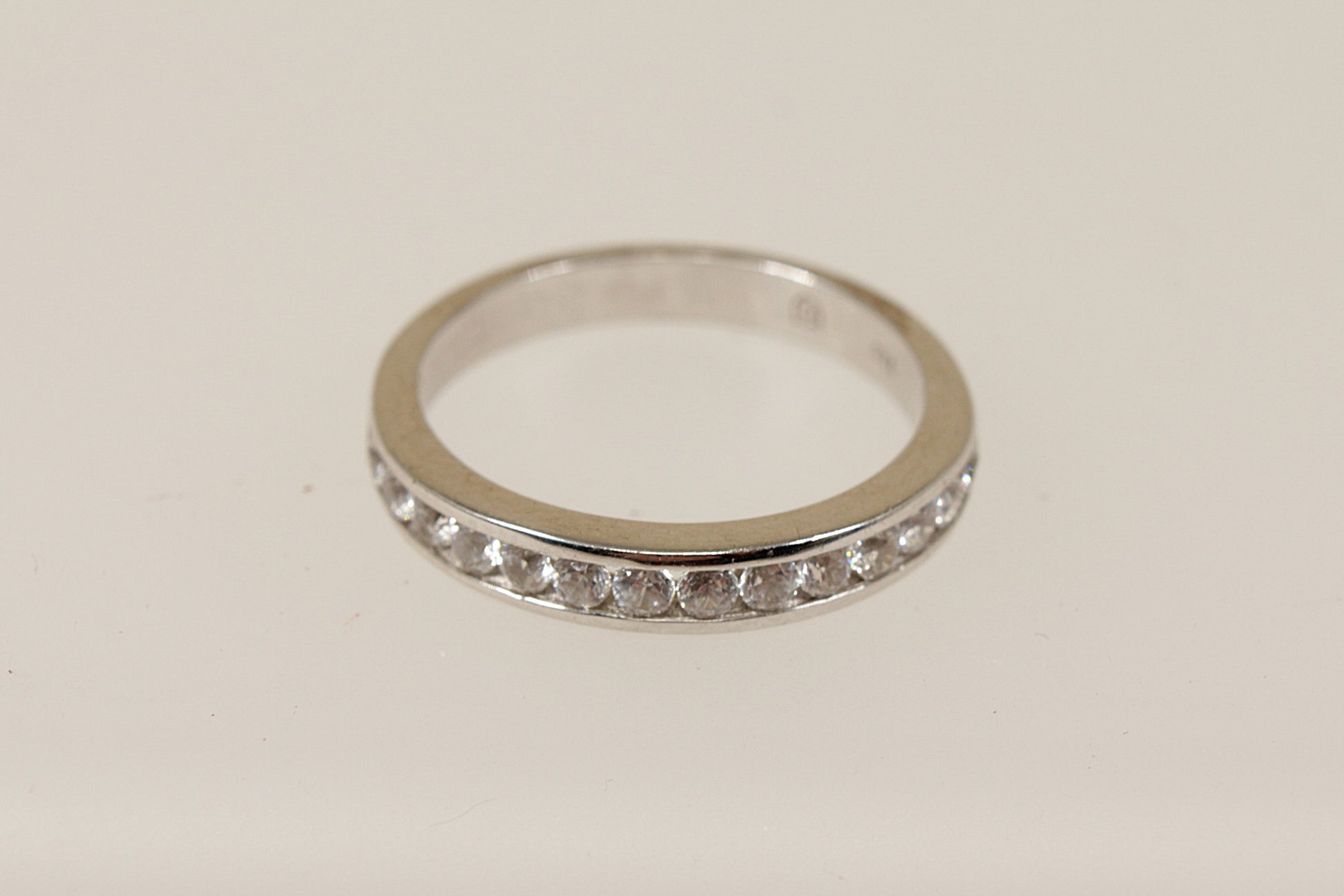 A silver white topaz half eternity ring with channel setting, displayed against a white background.