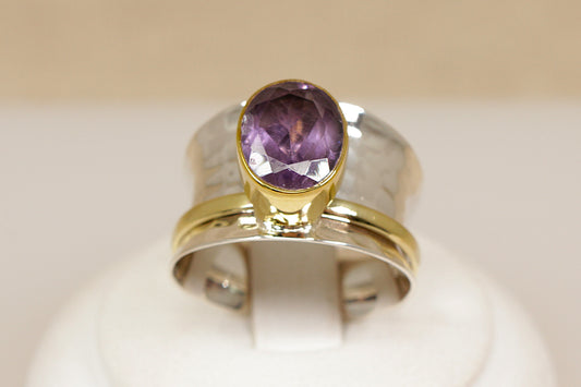 Ring with a purple amethyst gemstone and gold band on a beige background