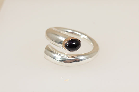 The bold, chunky rounded band is open-ended and curves gracefully to form a unique, modern silhouette. Set at the open terminal is a rich oval Blue Iolite, bezel set and accented with a warm silver gilt bezel, adding a touch of contrast and luxury to the cool silver tones. The interior of the band is stamped 925, UK finger size M.