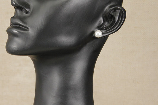 Mannequin head with a pearl earring on a beige background