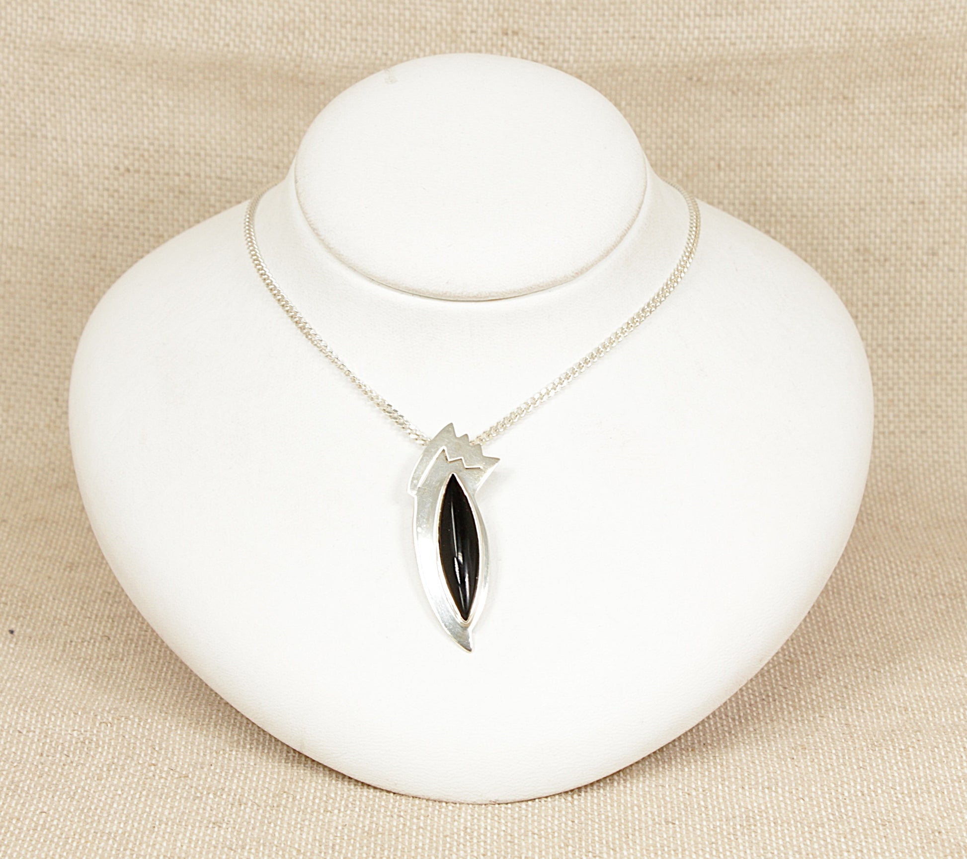 Silver and Onyx Abstract ‘Bird of Paradise’ Pendant and Chain necklace.
An eye-catching and artistic modernist silver pendant, designed in the form of an abstract bird of paradise. At its centre is a smooth, marquise-shaped domed cabochon onyx, forming the elegant body of the bird with a rich, glossy black finish that adds depth and drama to the piece.