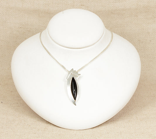 Silver and Onyx Abstract ‘Bird of Paradise’ Pendant and Chain necklace.
An eye-catching and artistic modernist silver pendant, designed in the form of an abstract bird of paradise. At its centre is a smooth, marquise-shaped domed cabochon onyx, forming the elegant body of the bird with a rich, glossy black finish that adds depth and drama to the piece.