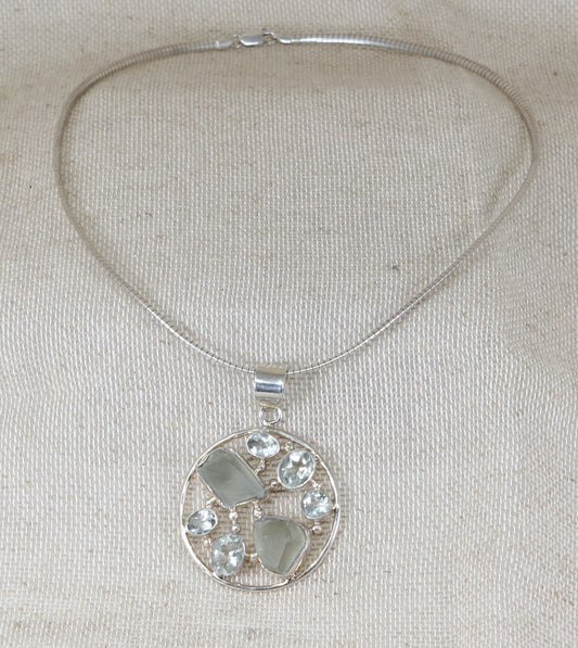 This gorgeous Silver collarette has a large round handcrafted pendant inset with faceted and raw Quartz gemstones in an asymmetric design. Made in Italy, this statement pendant sits on a snake chain collarette. Pendant size: 42mm round.