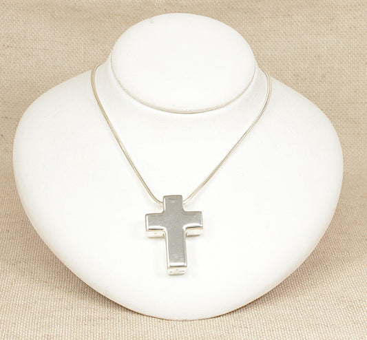 A finely crafted and substantial sterling silver cross pendant with a sleek, modern design featuring straight sides and smooth edges. The cross measures 1½ inches in length by 1 inch in width, offering a bold yet refined presence. 
The front is etched in large letters with “MM 2000 AD”. At the top, the pendant bears laser hallmarks for London 2000.