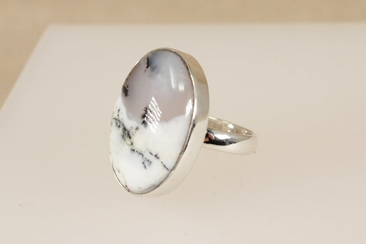 Silver ring with a large oval moss agate gemstone on a beige background