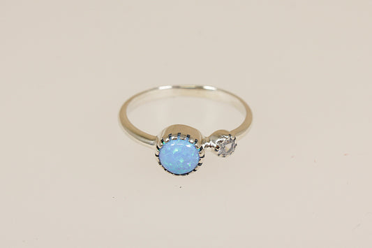 Silver ring with a blue opal and crystal gemstones on a beige background 
