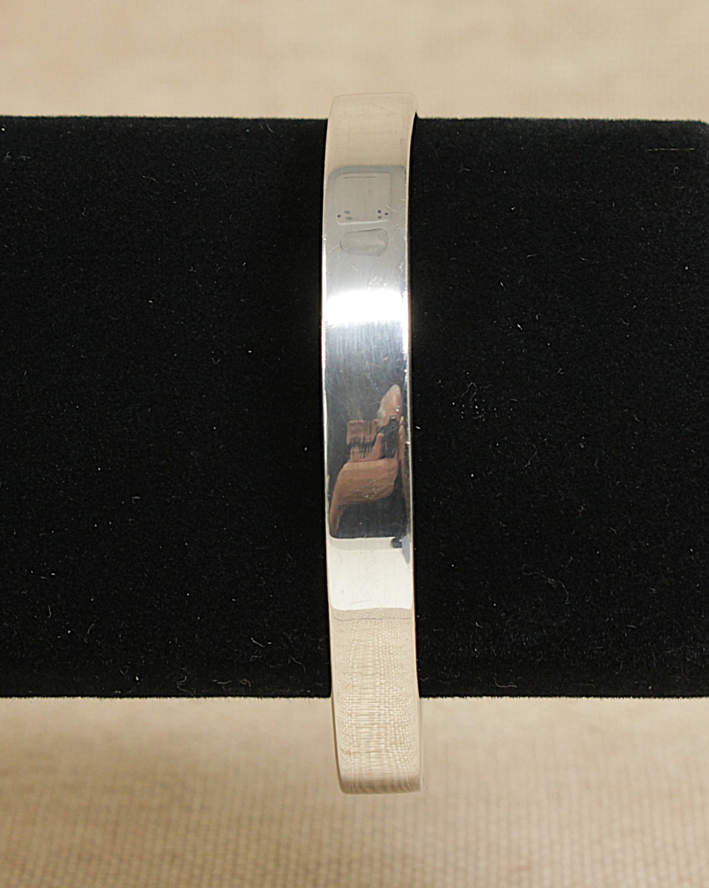 Silver bracelet on a black cushion with a beige background