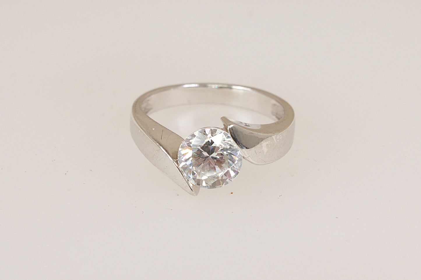 Silver solitaire ring with a simulated  diamond cubic zirconia gemstone on a light gray background