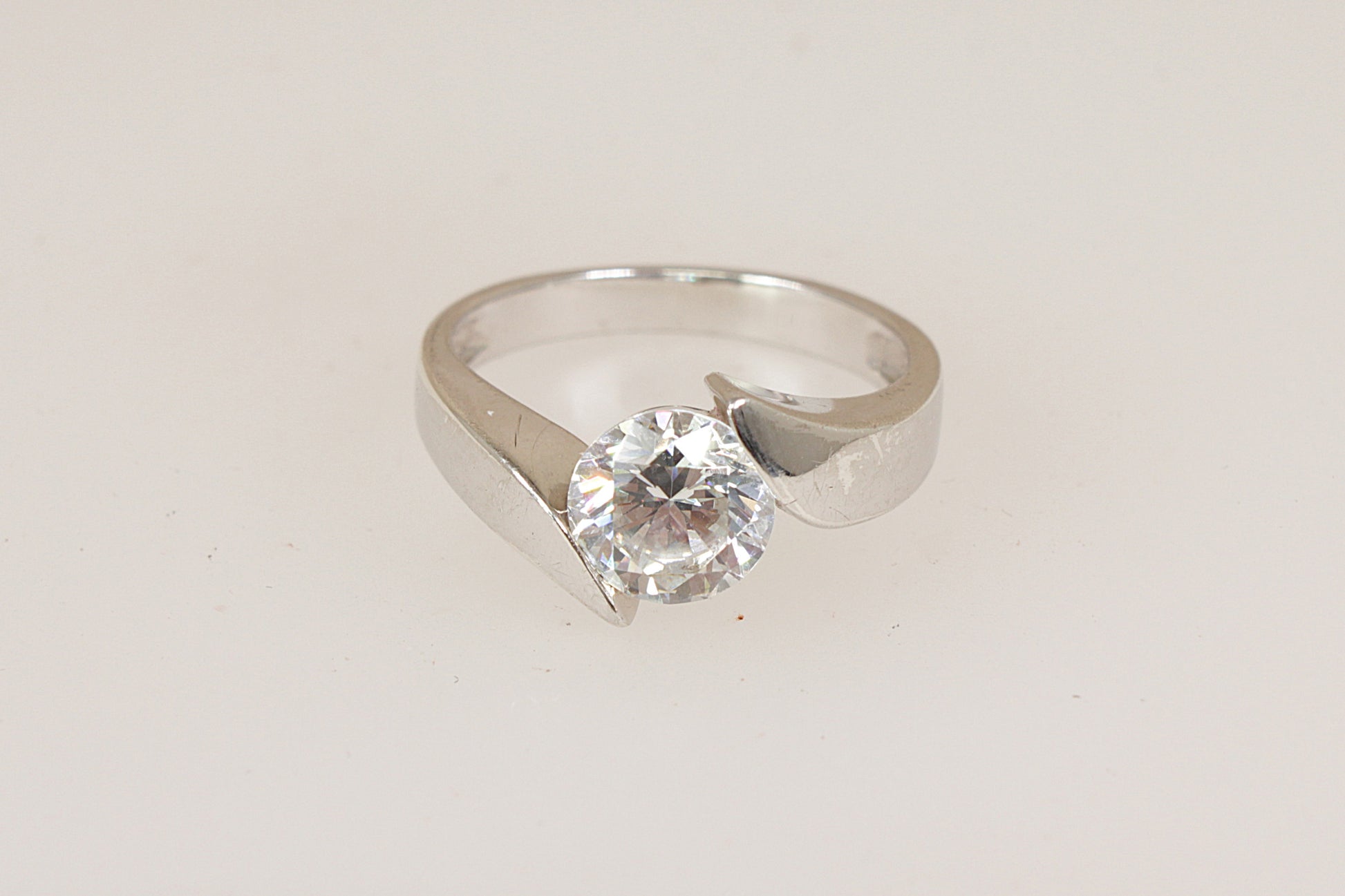 Silver solitaire ring with a simulated  diamond cubic zirconia gemstone on a light gray background