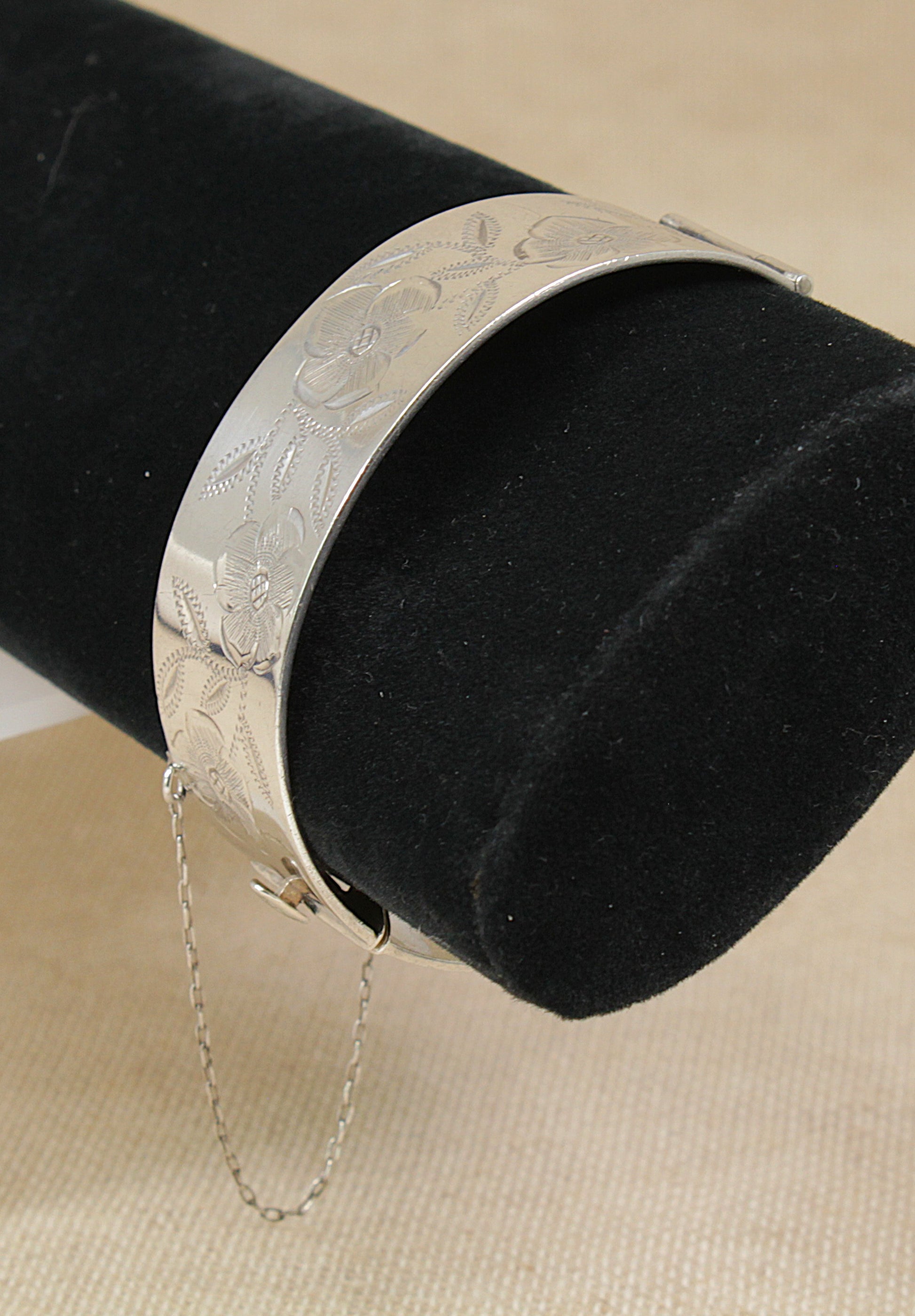 Vintage 1990's Solid Silver bracelet with intricate designs on a black velvet stand.