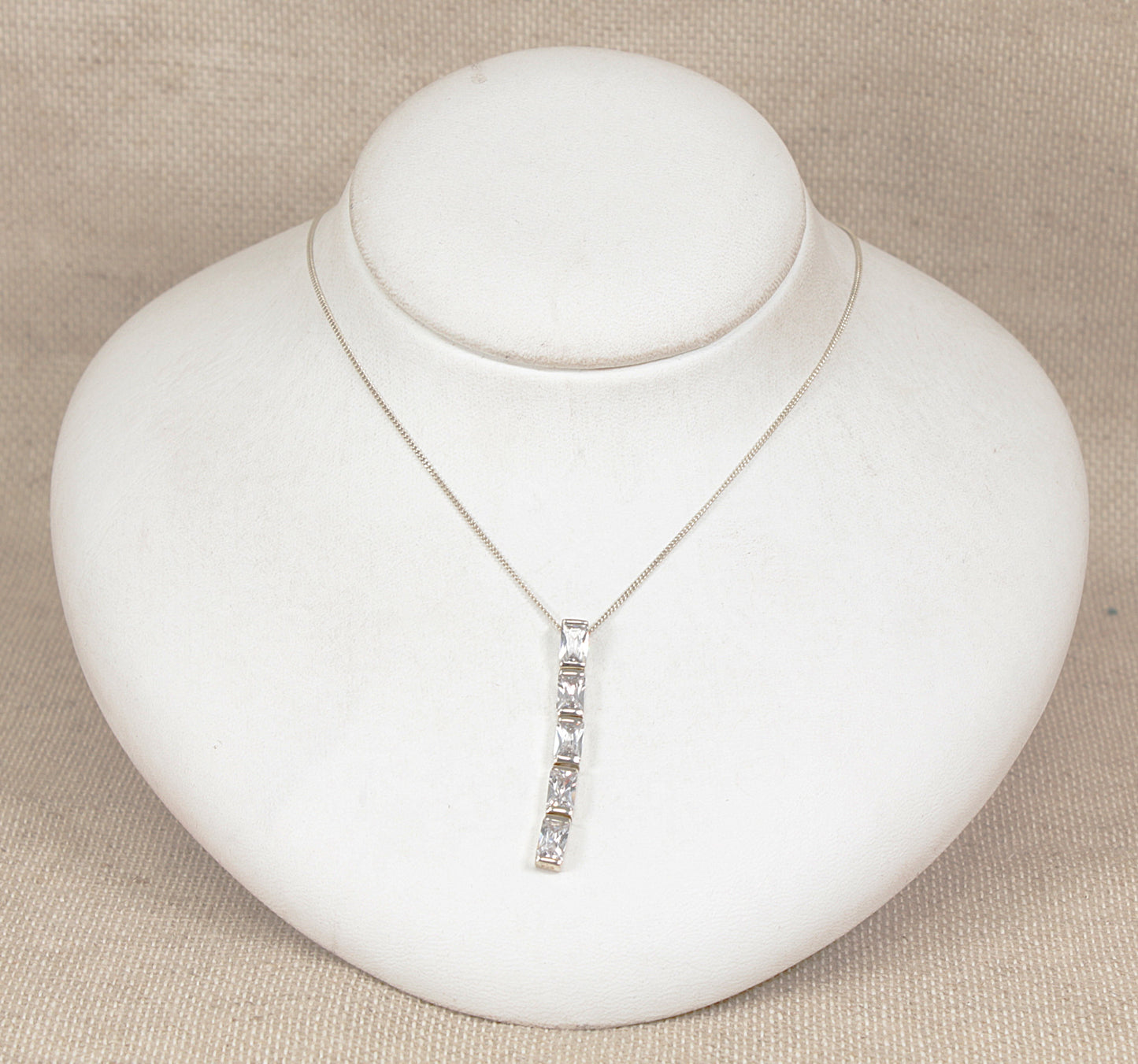 Silver necklace with a pendant on a white jewelry display