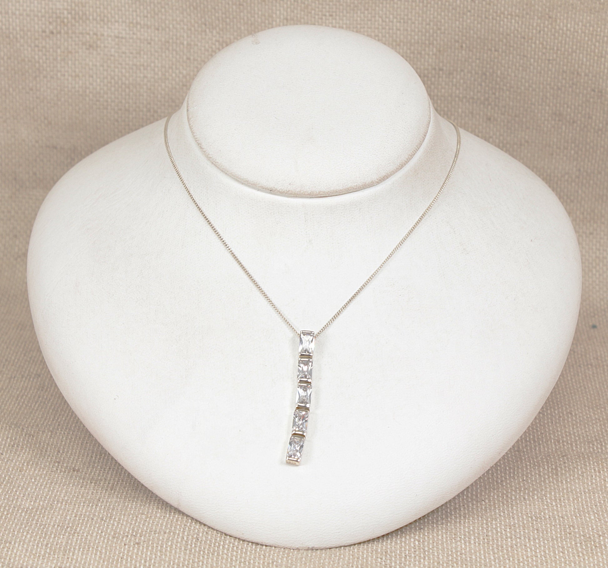 Silver necklace with a pendant on a white jewelry display