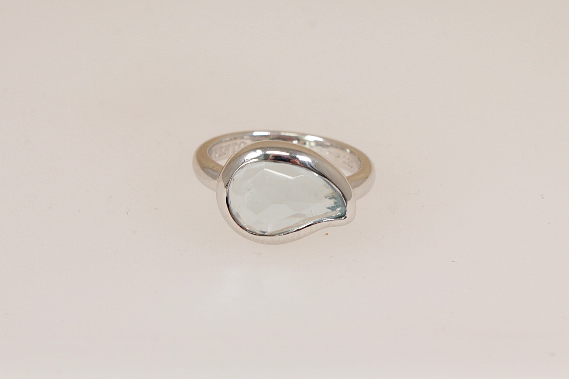 Silver designer ring by Italian maker 'Ti Sento' with a pale blue sem-precious gemstone on a light beige background