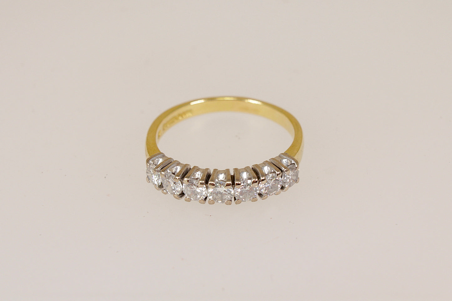 18ct 7 stone diamond eternity ring on a light beige background