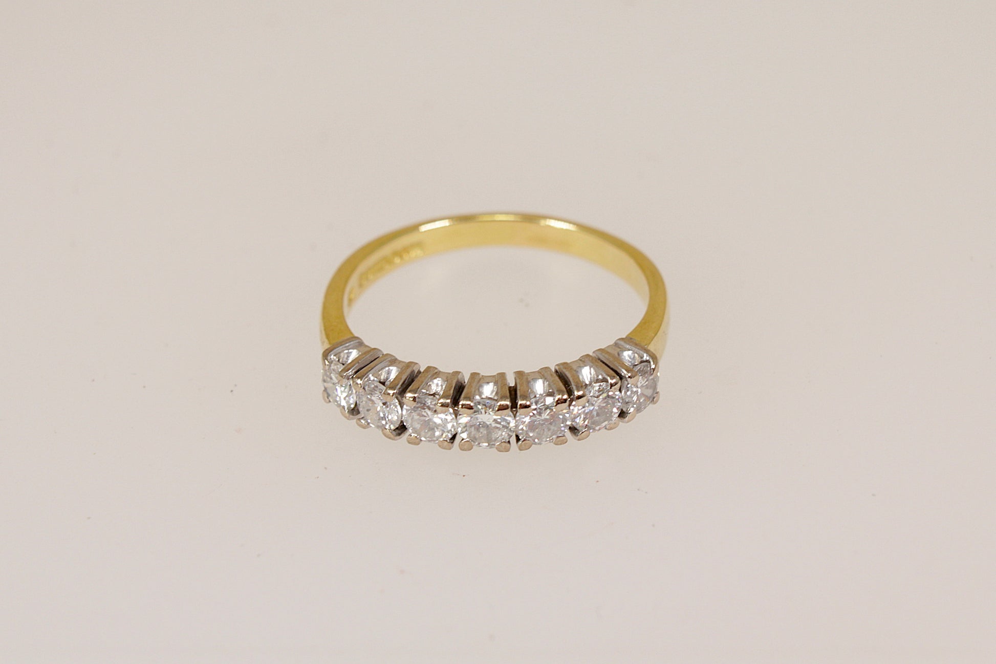 18ct 7 stone diamond eternity ring on a light beige background