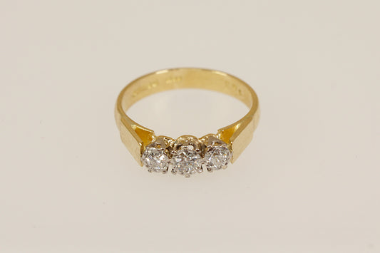 Gold ring with three diamonds on a beige background