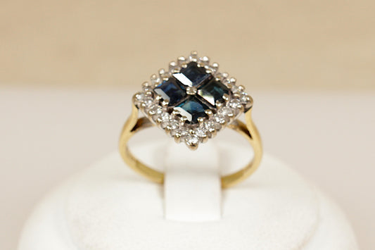 18ct Gold ring with blue sapphire gemstone and diamond accents on a beige background