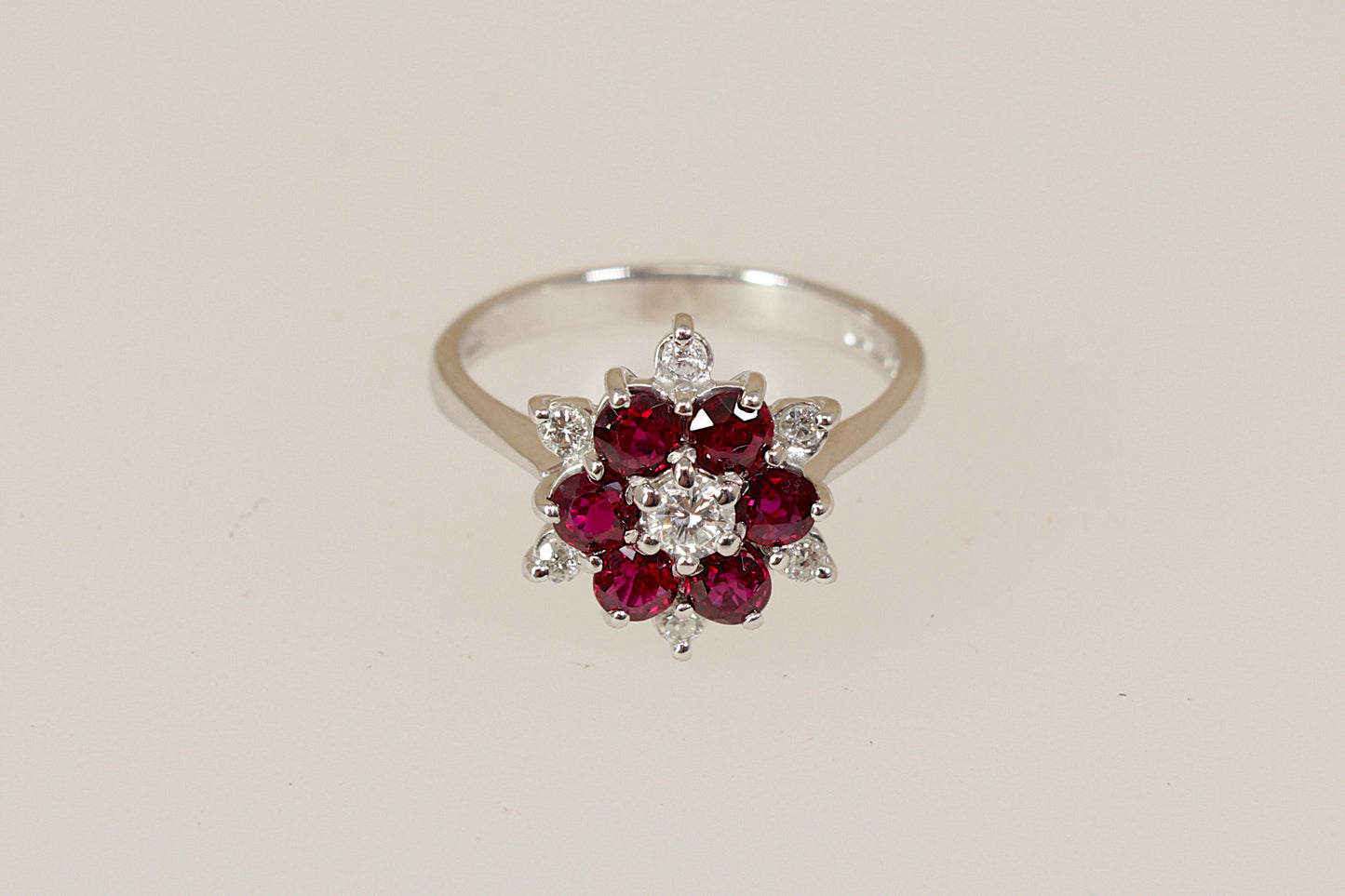 18ct white gold ring with rich red rubies and round brilliant diamond  gemstones on a beige background 