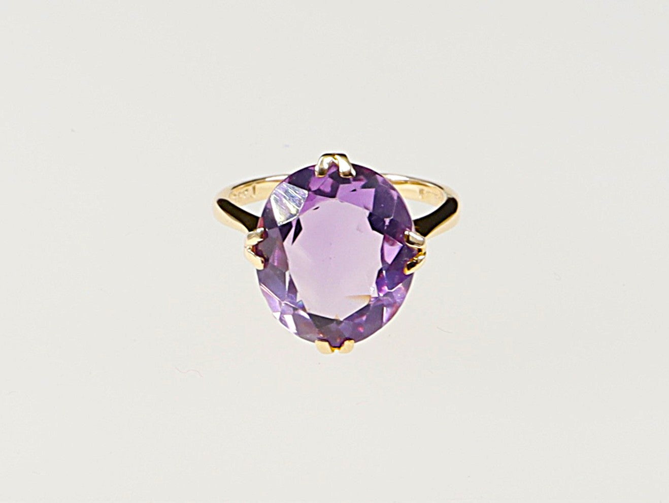 A vintage 9ct gold solitaire ring with a large amethyst gemstone, featuring a double claw basket setting.