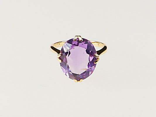 A vintage 9ct gold solitaire ring with a large amethyst gemstone, featuring a double claw basket setting.