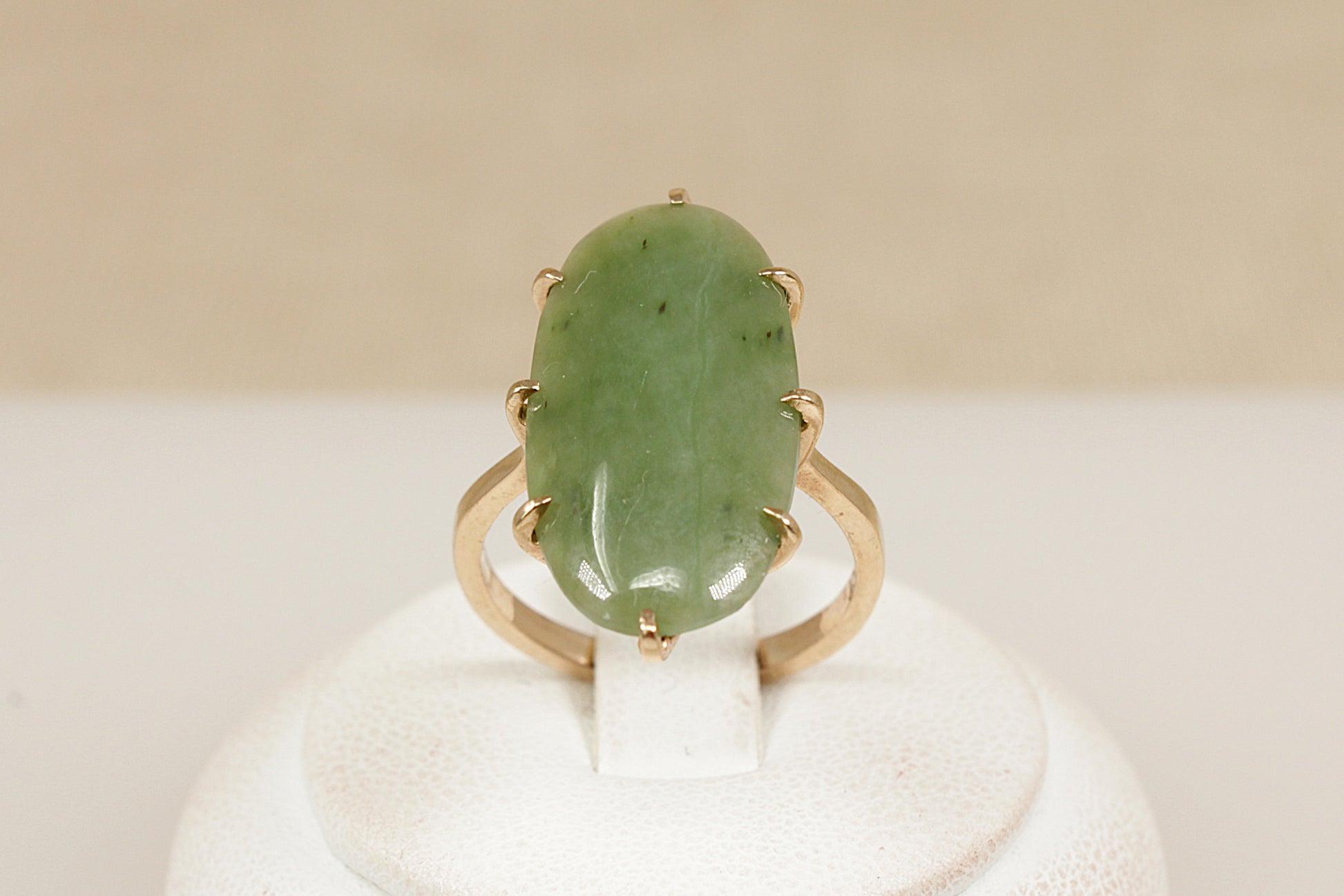 A graceful vintage ring crafted in solid 9ct yellow gold, showcasing a striking navette-shaped Jadeite cabochon. The smooth, polished surface of the Jadeite is gently domed, with natural inclusions visible—typical of authentic, untreated jadeite and adding to its organic charm. The inside of the band is stamped ‘9ct’, UK finger size N.