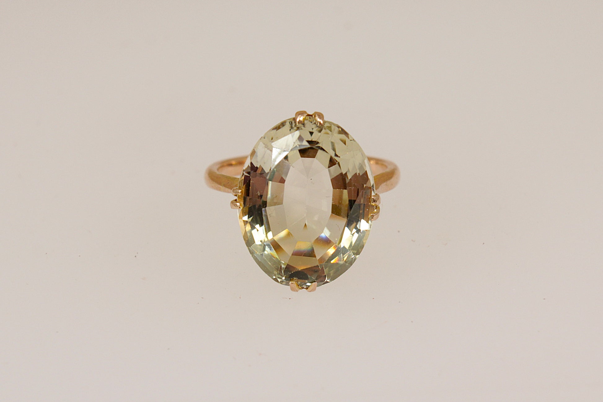 Gold ring with a large lemon citrine  gemstone on a beige background