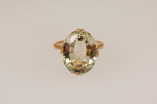 Gold ring with a large lemon citrine  gemstone on a beige background