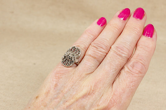 Hand with pink nail polish wearing a silver ring on a beige background