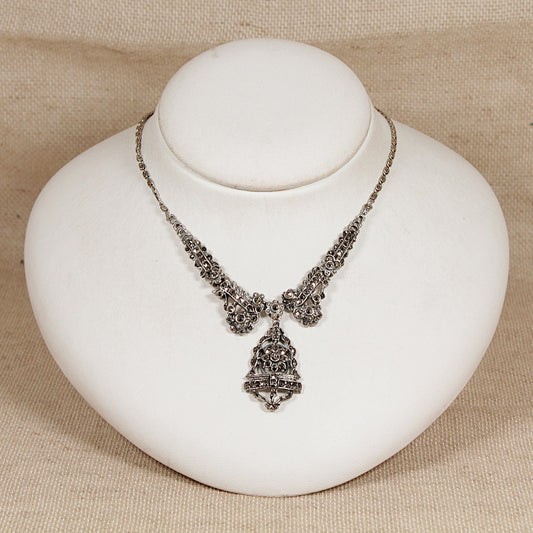 Art Deco silver marcasite necklace with a pendant on a white stand against a beige background