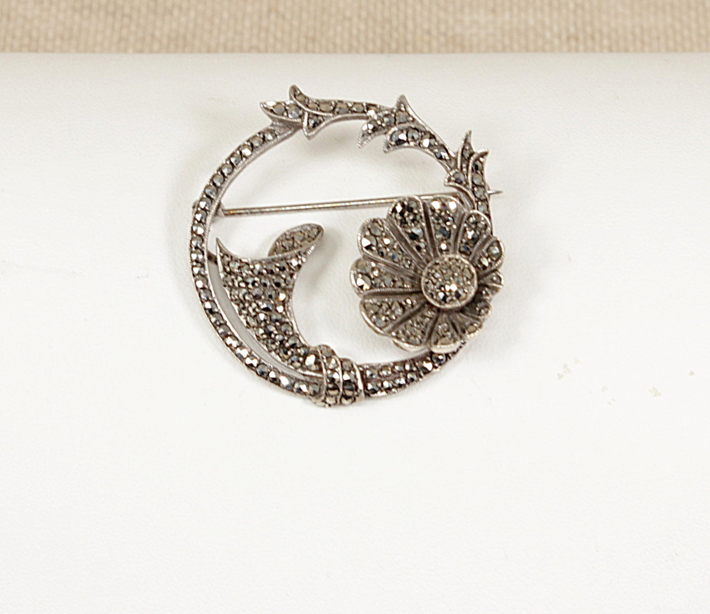 Decorative silver and marcasite art nouveau brooch with floral design on a white background 